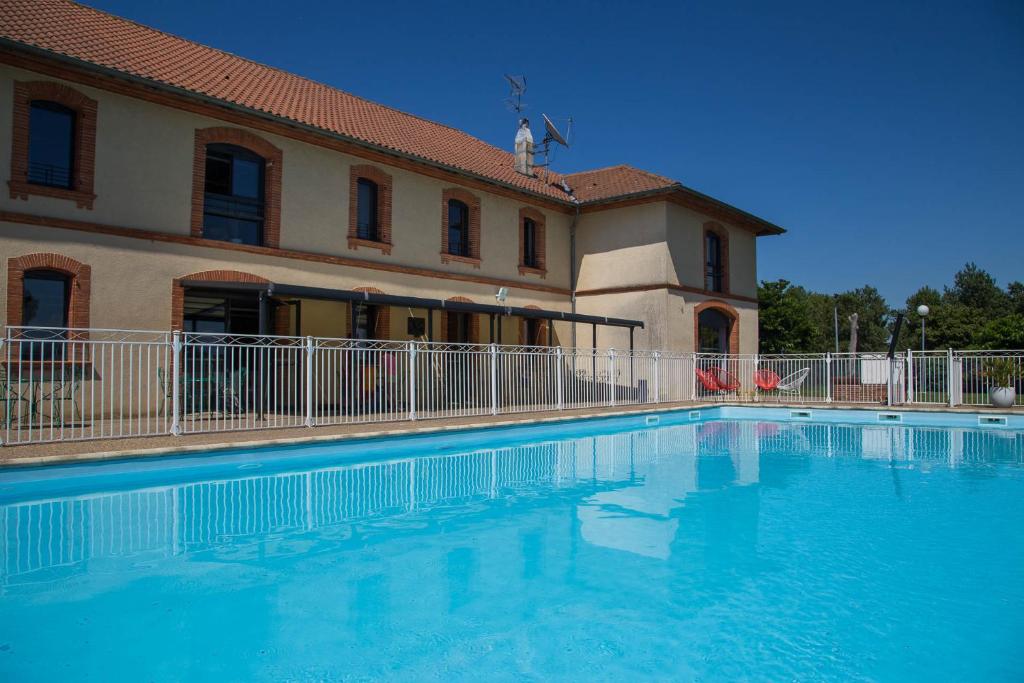 a large swimming pool in front of a building at Domaine de Garabaud in Mazères