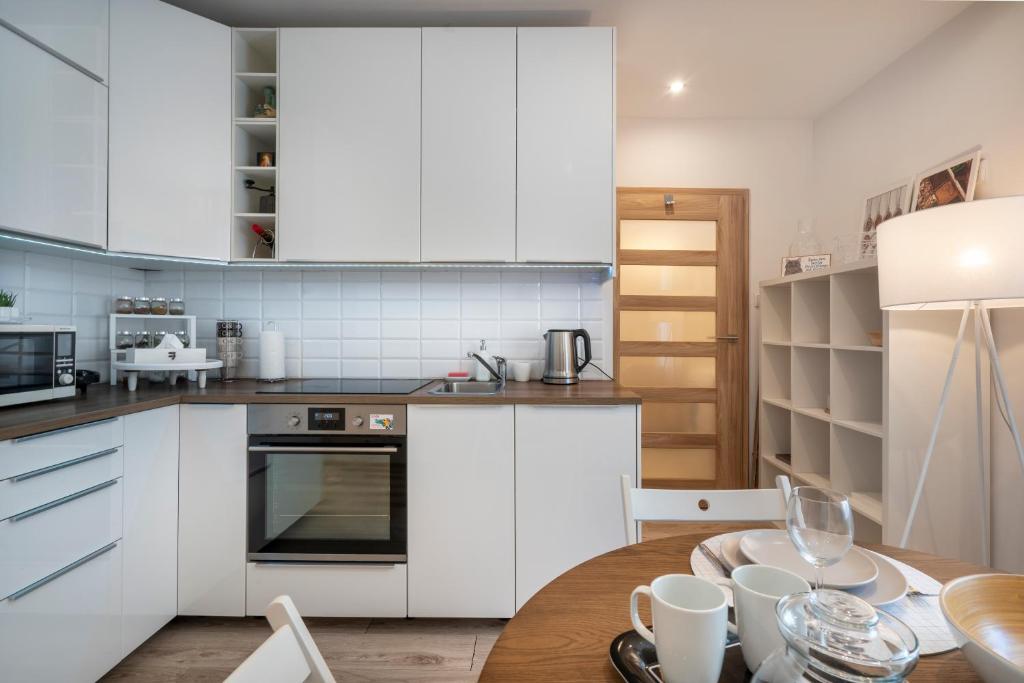 a kitchen with white cabinets and a wooden table at 06 Gdynia Centrum - Apartament Mieszkanie dla 4 os in Gdynia