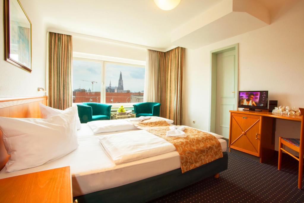 a hotel room with a large bed and a window at Centro Hotel Royal in Cologne