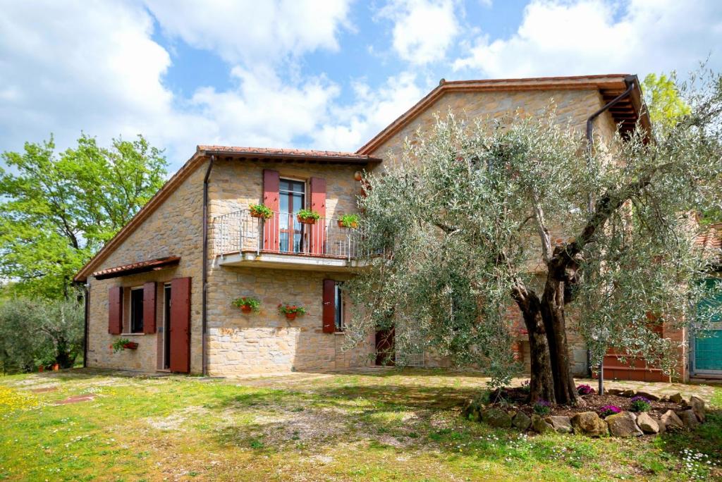 una vieja casa de piedra con un árbol delante en Villa Profumo di Salvia, en Magione