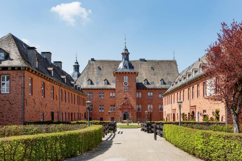 um pátio de um grande edifício de tijolos com uma torre de relógio em Ferienwohnung Saalstube - Schloss Adolphsburg em Kirchhundem