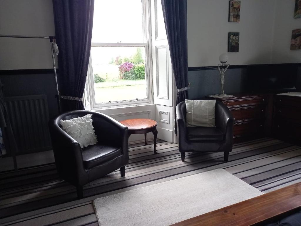 a living room with two chairs and a window at Gardenvale Manor House B&B in Stranocum