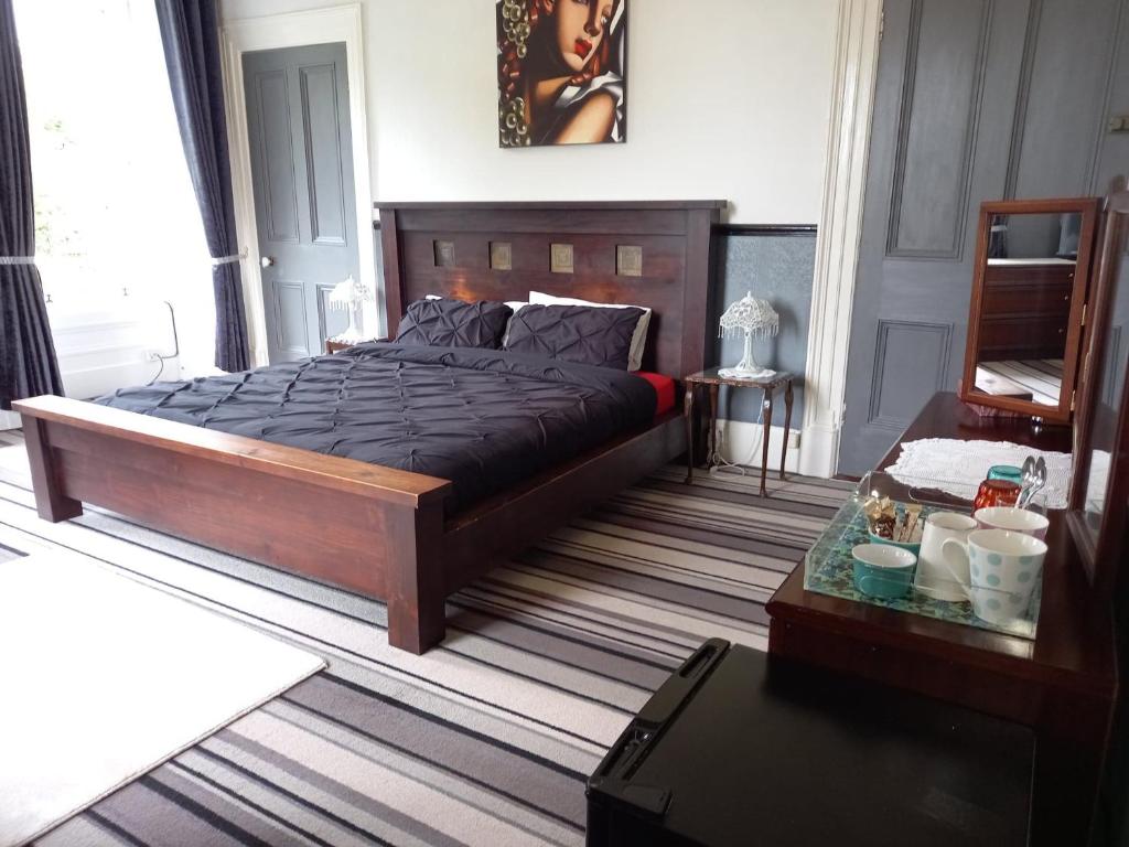 a bedroom with a large bed and a table at Gardenvale Manor House B&B in Stranocum