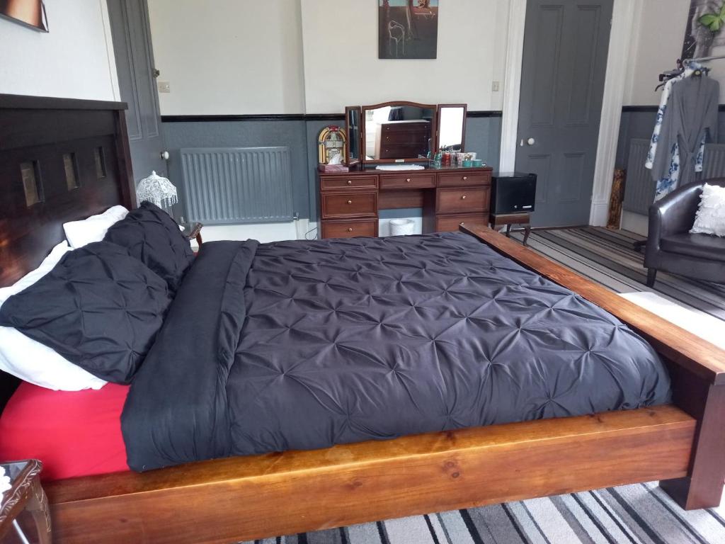 a bedroom with a large bed with a wooden frame at Gardenvale Manor House B&B in Stranocum