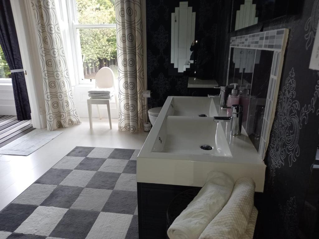 a bathroom with a white sink and a mirror at Gardenvale Manor House B&B in Stranocum