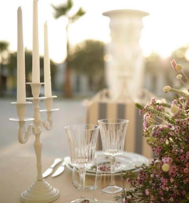 a table with two white candles and glasses on it at Hotel Villa Pascucci in Durrës