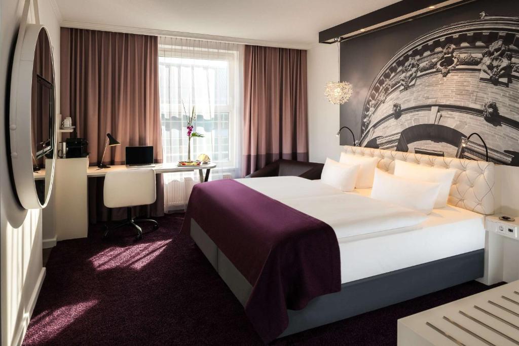 a hotel room with a large bed and a desk at Dorint Kongresshotel Mannheim in Mannheim