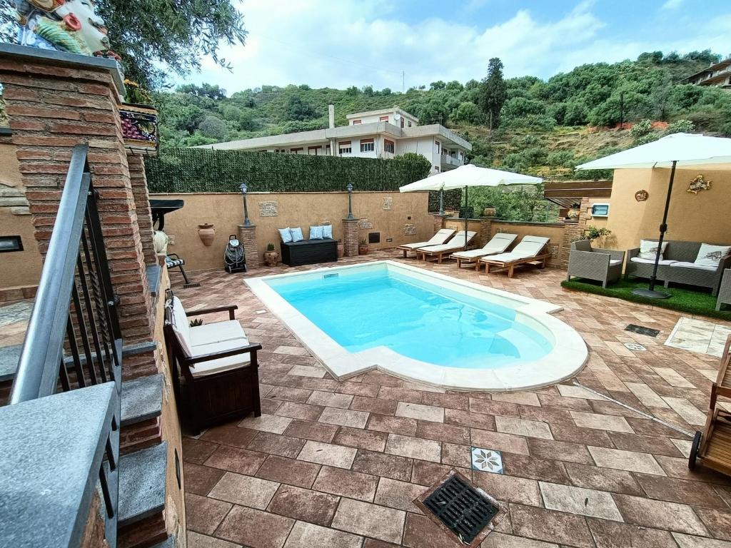 サンタレッシオ・シークロにあるVilla Alecla - Sea Villa near Taorminaのパティオ(椅子、パラソル付)のスイミングプール