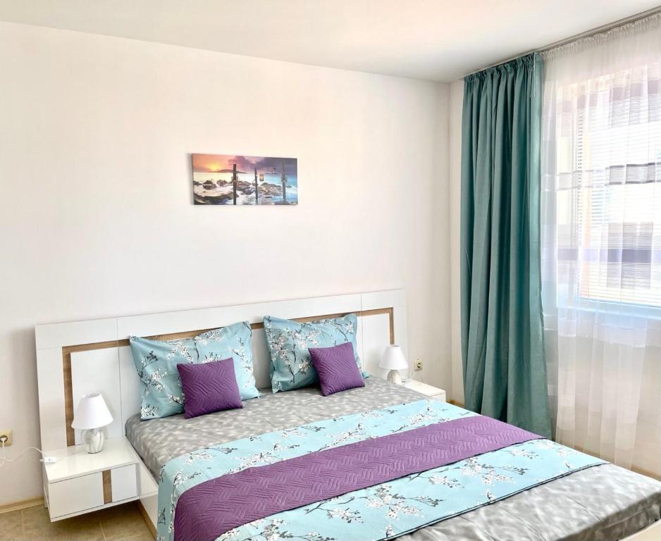 1 dormitorio con 1 cama con almohadas moradas y azules en Rusalka Apart-Residence en Obzor