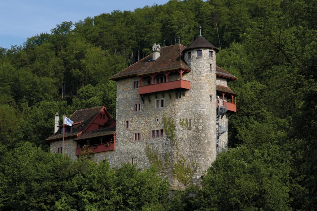 Mariastein-Rotberg Youth Hostel في Mariastein: مبنى قلعة على قمة تل به اشجار