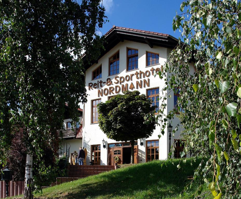 a white building with a sign on the front of it at Reit-und Sporthotel Nordmann in Stangerode