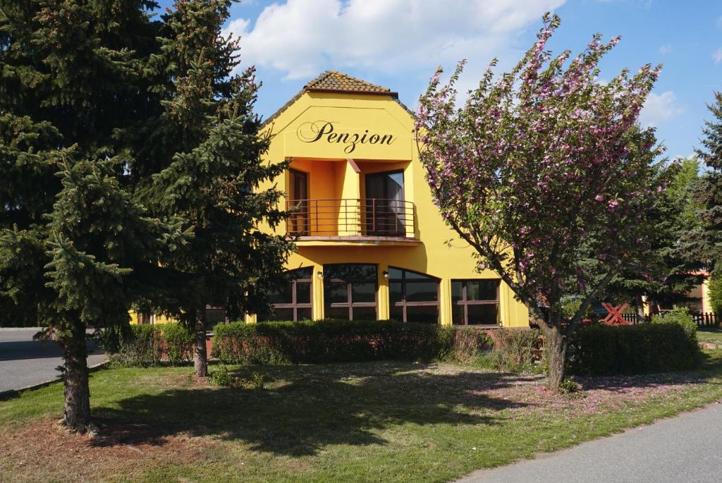 a yellow house with a balcony and trees at LEO - PENZION in Jevišovice