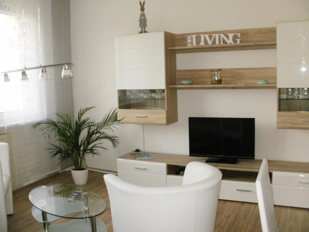 ein Wohnzimmer mit einem TV, einem Tisch und Stühlen in der Unterkunft Ferienwohnung Zierold in Zwenkau