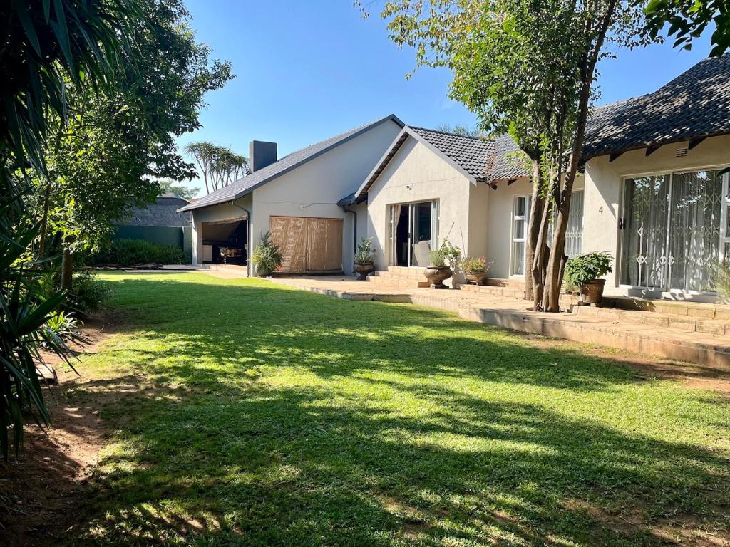 une maison avec une grande pelouse devant elle dans l'établissement Lenox Lodge Guesthouse, à Johannesbourg