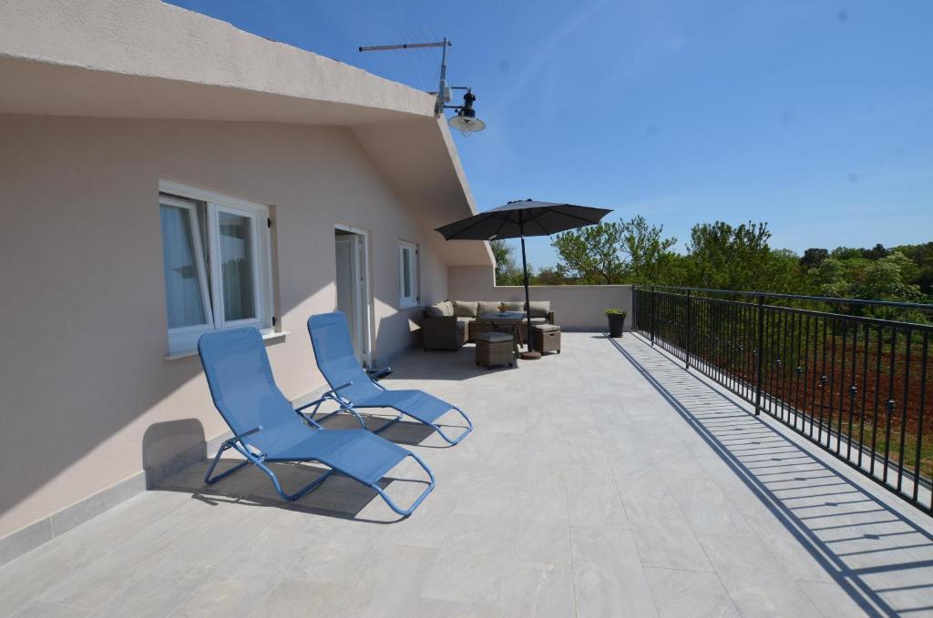 dwa niebieskie krzesła i parasol na balkonie w obiekcie Casa Nini w Rovinj