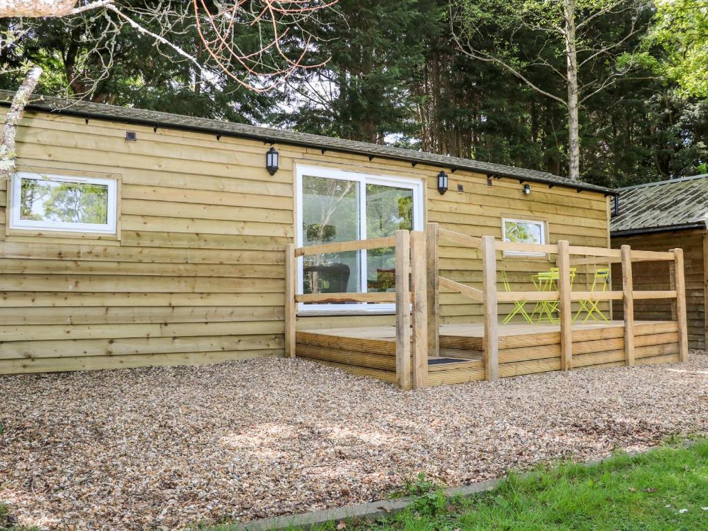 a wooden building with a gate and a fence at Harvest Lodge in Haywards Heath