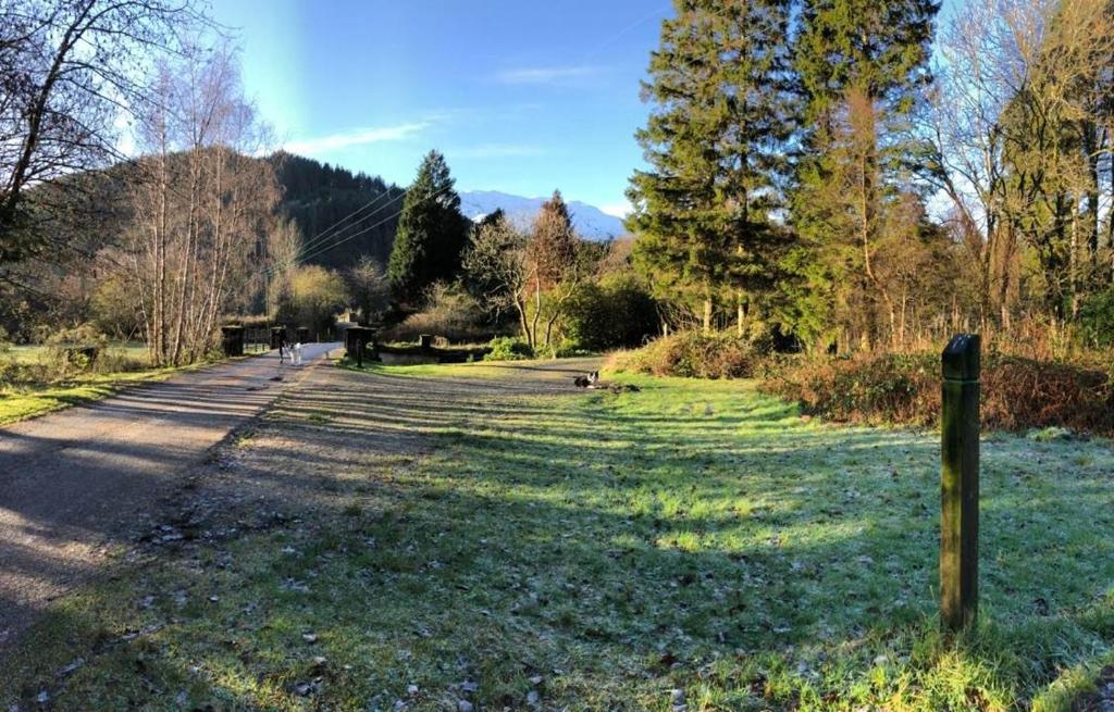 een weg met een hek aan de zijkant van een veld bij 24 Glenfinart Park in Dunoon