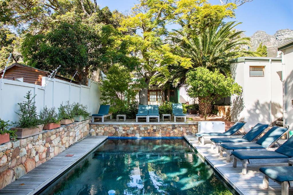 a swimming pool with lounge chairs and a retaining wall at Stone Cottages in Cape Town