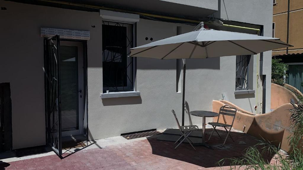 un patio con sombrilla, mesa y sillas en Bologna Facile, en Bolonia