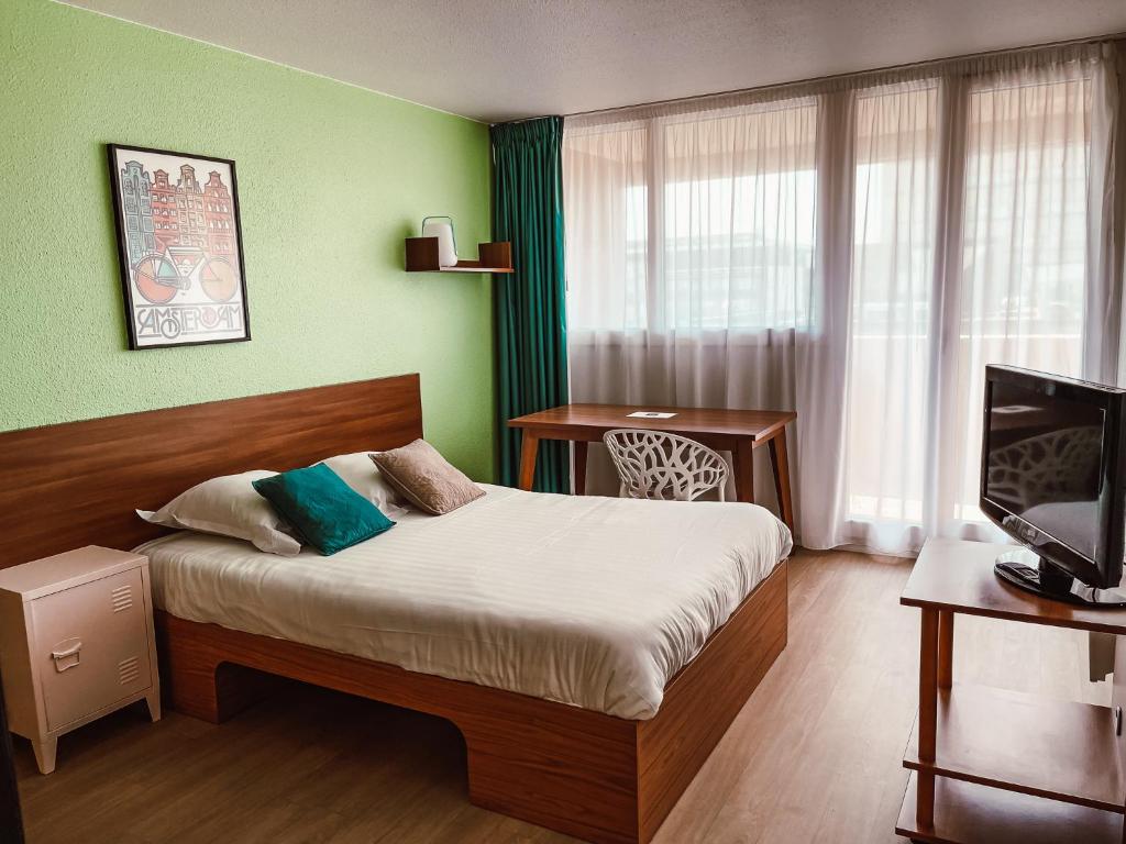 una habitación de hotel con una cama y un televisor en UXCO Grenad'inn, en Burdeos