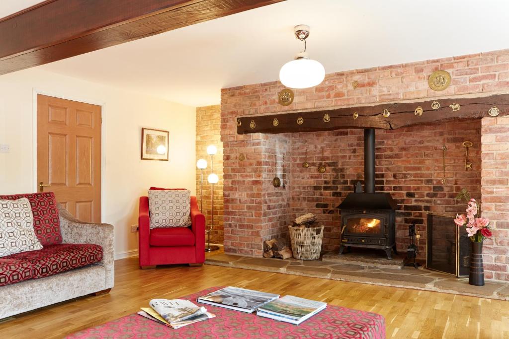 a living room with a brick fireplace and a red couch at Finest Retreats - Willow Barn in Ashbourne