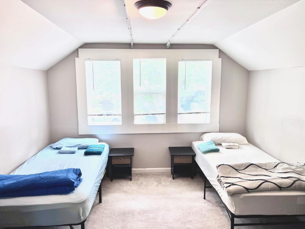 two beds in a room with two windows at WHOLE Family - Oak Park in Sacramento