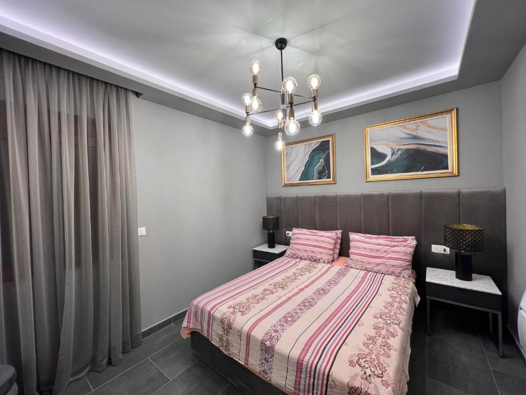 a bedroom with a bed with pink pillows and a chandelier at Varja 3 Apartment in Pržno