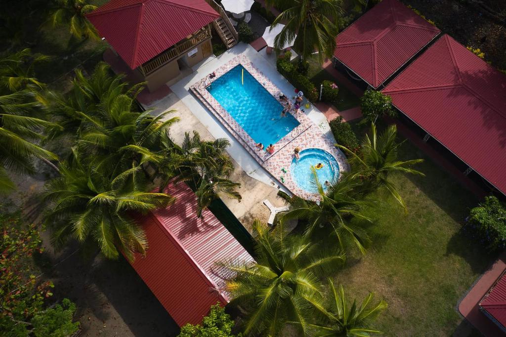 an overhead view of a pool with palm trees and umbrellas at Tranquilidad Resort in Parrita
