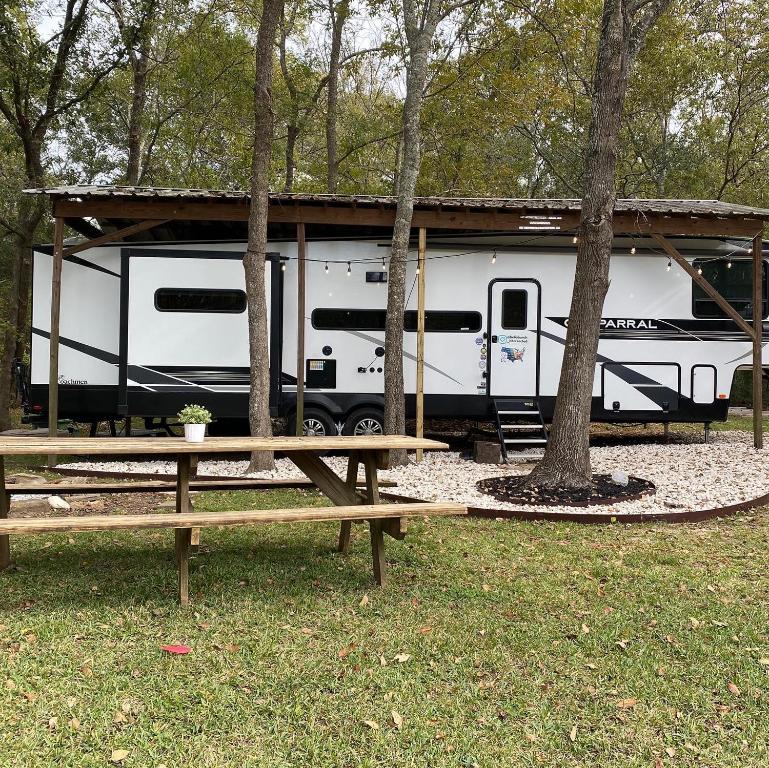 a white rv parked in front of trees at Cozy RV Experience w/POOL+SPA Near Lake Conroe in Willis