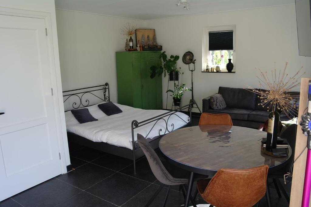 um quarto com uma cama, uma mesa e um sofá em De Parel B&B em Breezand