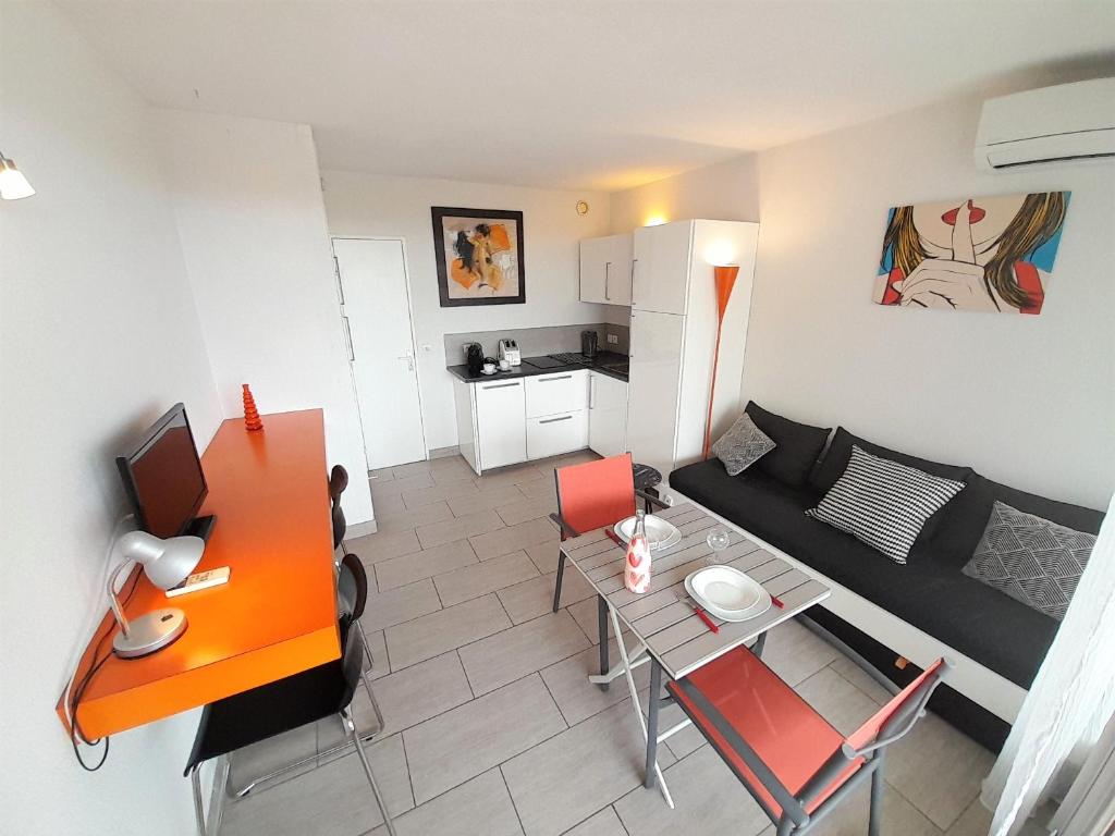 ein kleines Wohnzimmer mit einem Sofa und einem Tisch in der Unterkunft Appartement Village Naturiste Tornado in Cap d'Agde
