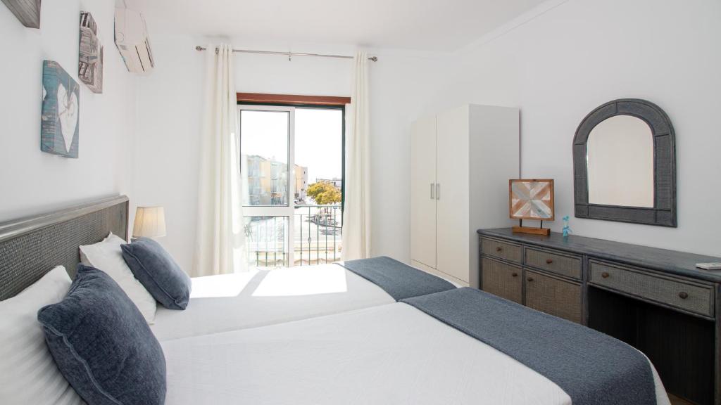 a bedroom with two beds and a dresser and a mirror at Altura Vacations T2, Algarve in Altura