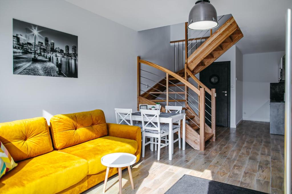 - un salon avec un canapé jaune et une table dans l'établissement Morris Apartamenty, à Chłopy