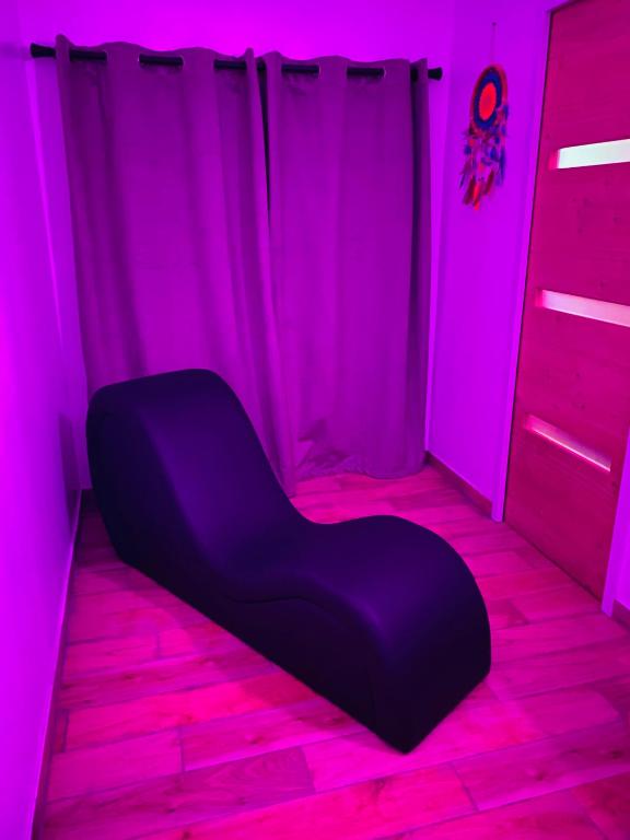 a black chair in a room with pink lights at Suite Cupidon- Domaine des trois châteaux in Moisenay