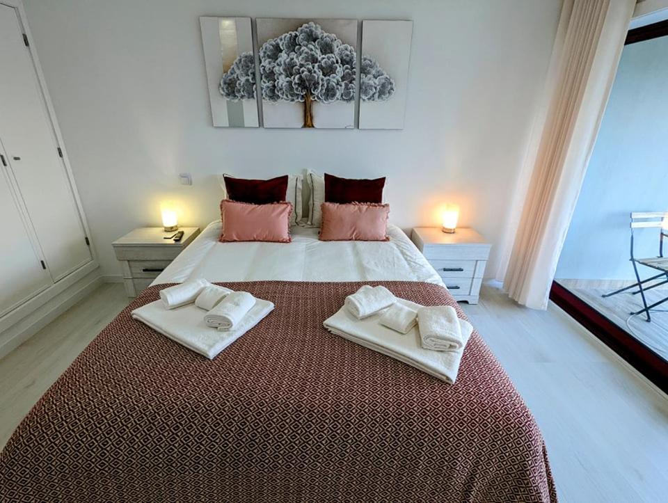 a bedroom with a large bed with two towels on it at Silvaapartments in Praia da Barra