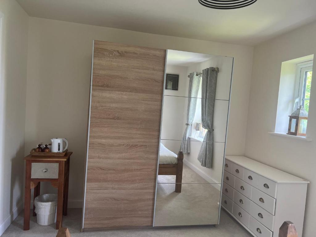 a large mirror in a room with a bedroom at Cosy double room with private bathroom homestay in Caldecote