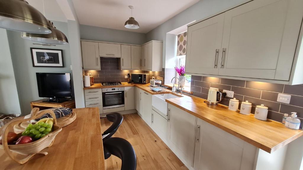 a kitchen with white cabinets and a wooden counter top at Deeside Holiday Cottages in Dinnet
