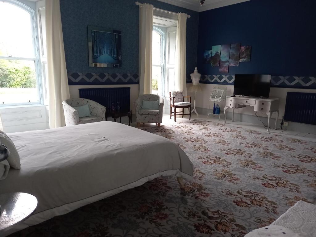 a bedroom with a large white bed and blue walls at Gardenvale Manor House B&B in Stranocum