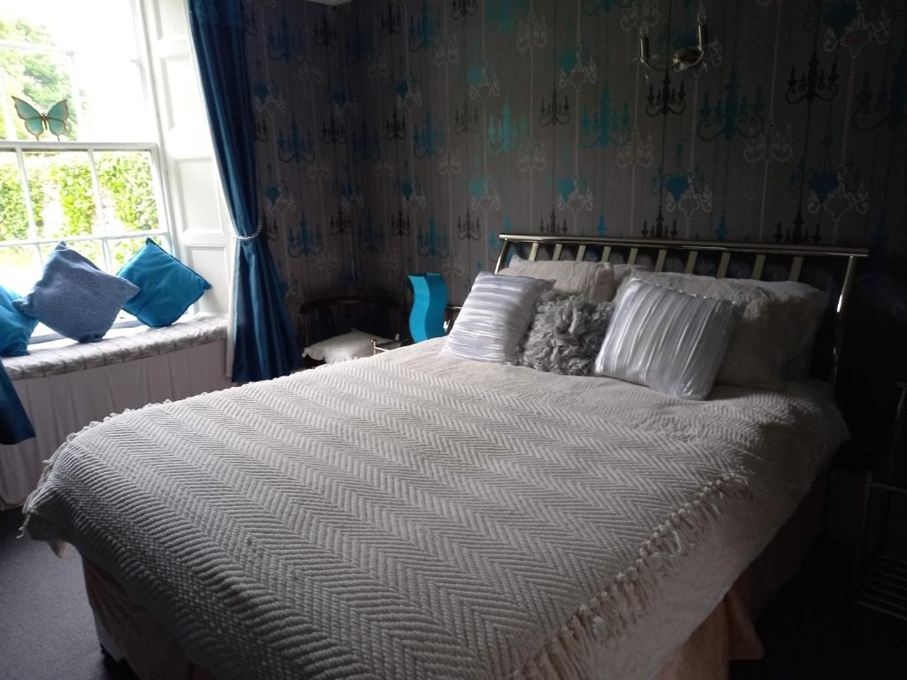 a bedroom with a bed with white sheets and a window at Gardenvale Manor House B&B in Stranocum