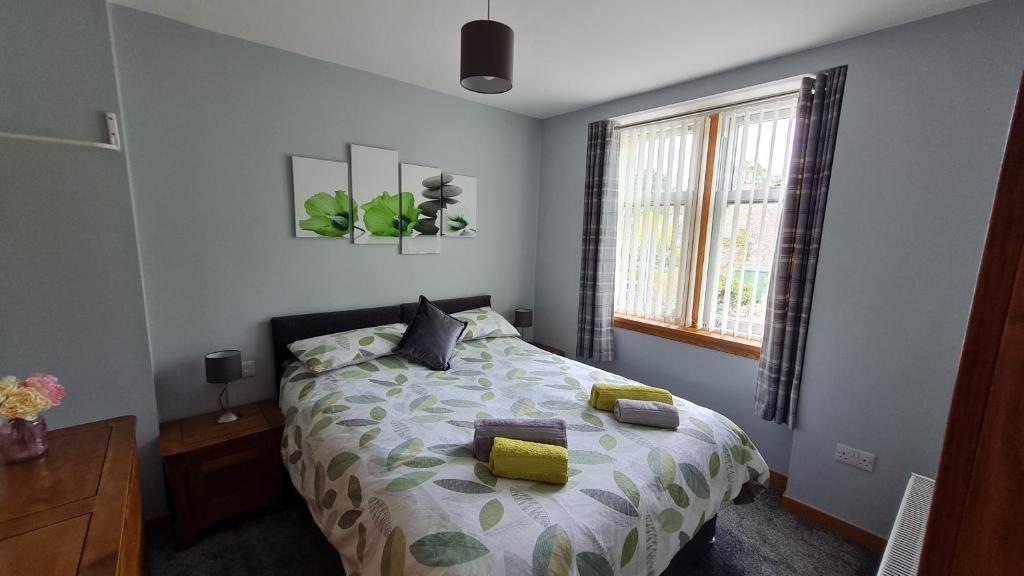 a bedroom with a bed with yellow pillows and a window at Deeside Holiday Cottages in Dinnet
