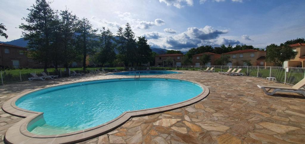 a large swimming pool in a yard with two chairs at Chez Twin&Twin in Santa-Maria-Poggio