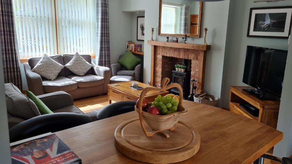 a living room with a table with a bowl of fruit on it at Deeside Holiday Cottages in Dinnet