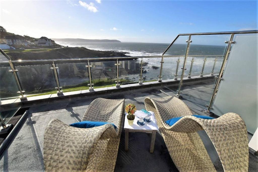 a balcony with chairs and a table and the ocean at Watersmeet Hotel in Woolacombe