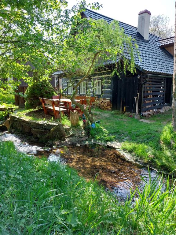 a house with a picnic table and a stream in front of it at Roubenka u potoka Výprachtice in Výprachtice