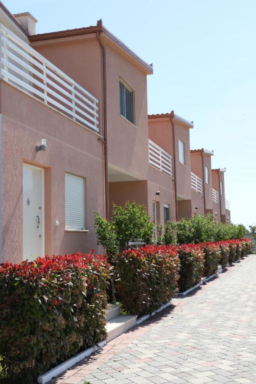 a row of houses with red flowers in front of them at Tea Residence, Gjiri i Lalzit Villa in Durrës