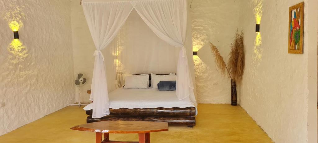 a bedroom with a canopy bed with a table at Posada Turistica Dantayaco in Mocoa