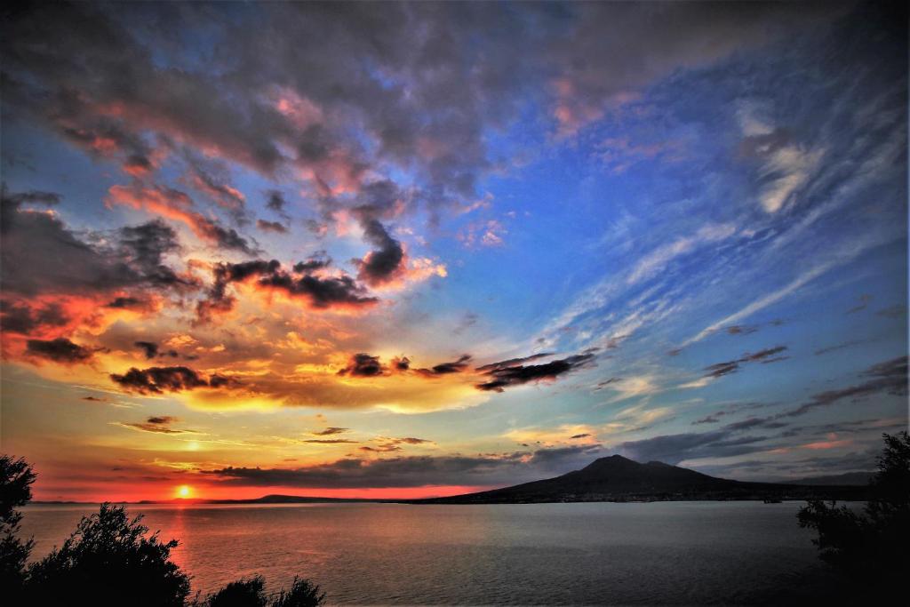 un coucher de soleil sur une étendue d'eau avec une montagne dans l'établissement Hotel Lucia, à Castellammare di Stabia