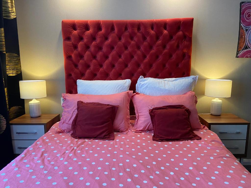 Garsoniera Riviera في باكاو: سرير مع اللوح الأمامي الأحمر والوسائد الزهرية