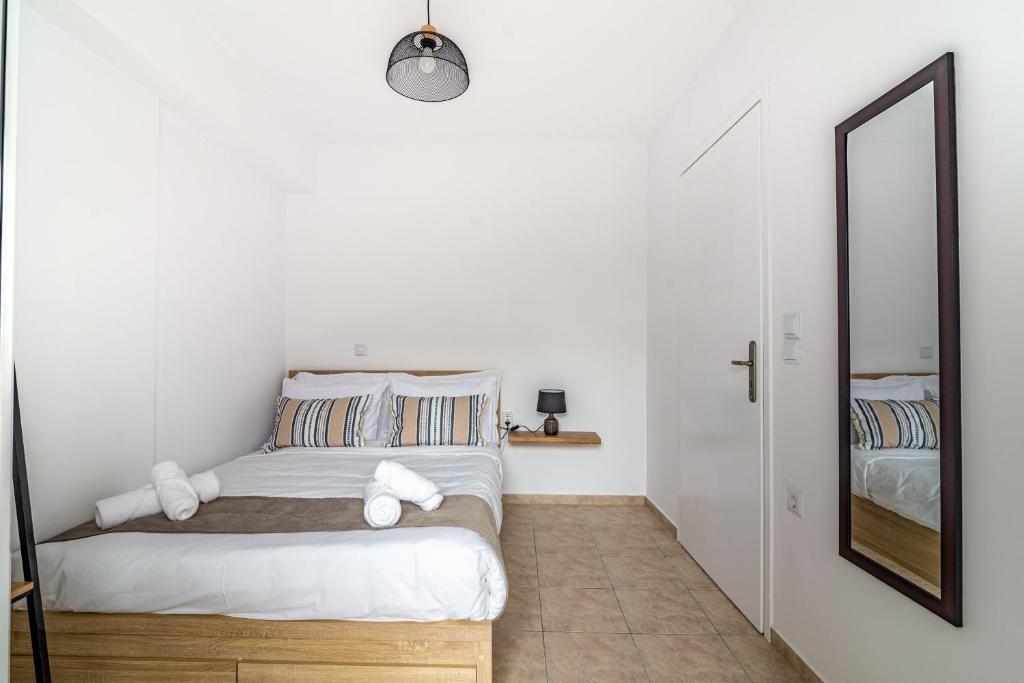 een witte slaapkamer met een bed en een spiegel bij Central Apartment Next To The Beachfront in Heraklion
