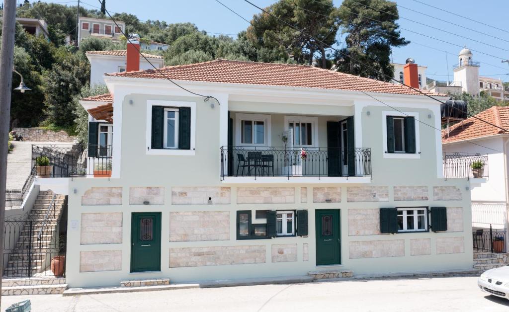 a white house with green doors on a street at Antheon apartments in Vathi